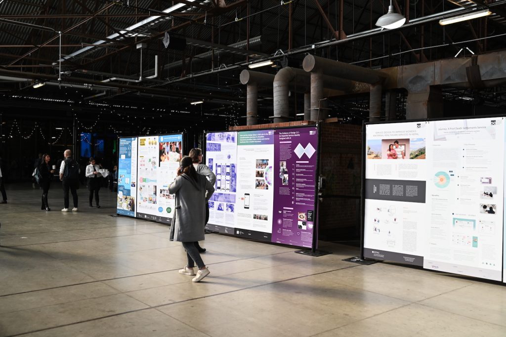 A person walks by displays of service design projects at SDGC